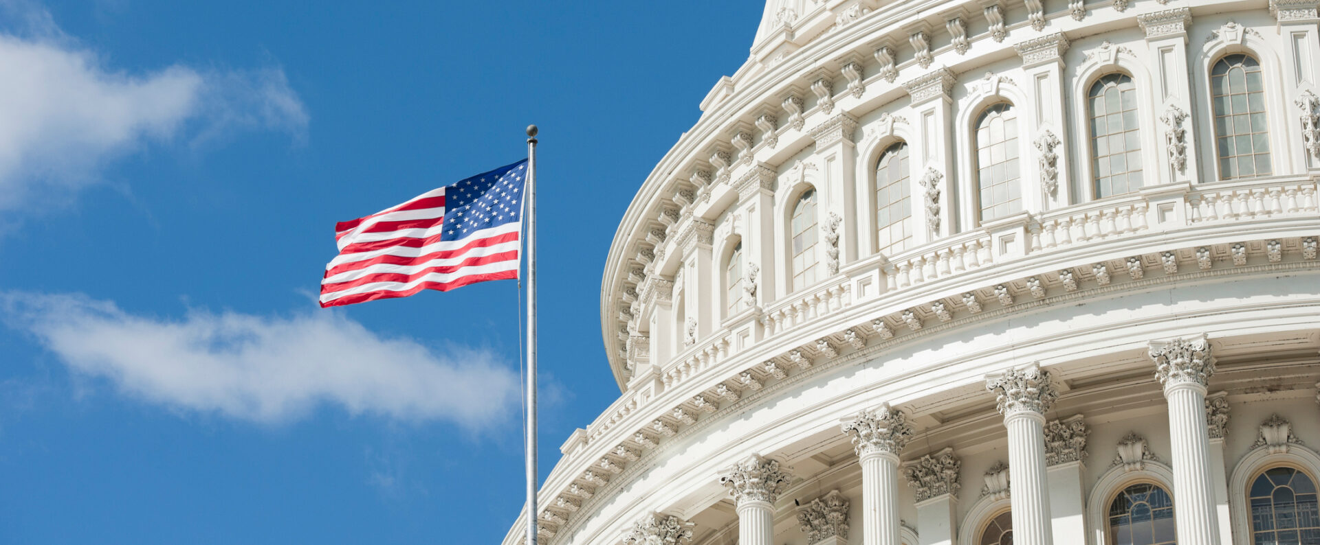 An American flag flies in front of a government building. EcoScribe provides audio transcription nationwide.